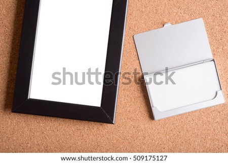 blank name card in case and blank black picture frame on wooden table