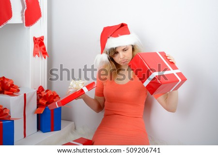 Girl in santa hat sitting by the fireplace with a gift box