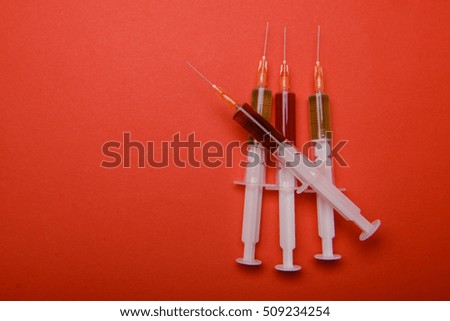 Hand in glove with syringe on red background. Injections.