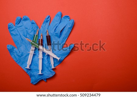 Hand in glove with syringe on red background. Injections.