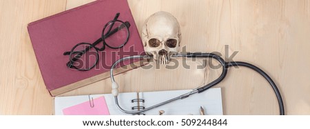 stethoscope , book note and skull on wood