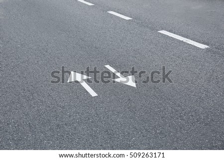 Arrow signs on asphalt road showing direction of movement
