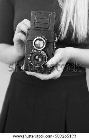 Pretty young girl with retro vintage camera standing and smiling against a colorfull wall