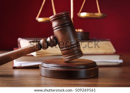 Judges gavel with justice scales and books on wooden table and red background