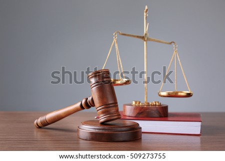 Judge's gavel with book and justice scales on wooden table and grey background