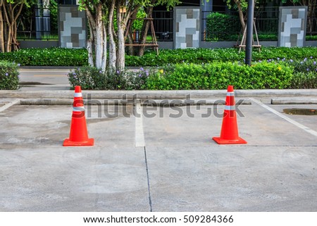 Orange Traffic Cone, traffic cone with white and orange stripes in parking lot.