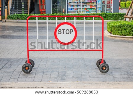 Red and white safety fence barrier with stop sign and wheel, steel panel to block entrances.