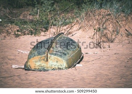 comfortable beach of the baltic sea with rocks and green vegetation and old boat in summer - vintage film look
