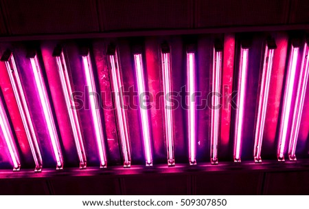bright crimson diagonal vertical long lamp against dark background, vertical lamps divided into sections with lights against dark background, high quality resolution, ceiling office lamp with light
