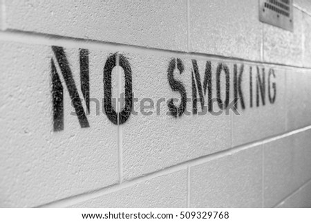 A no smoking sign painted on a cinder block wall.