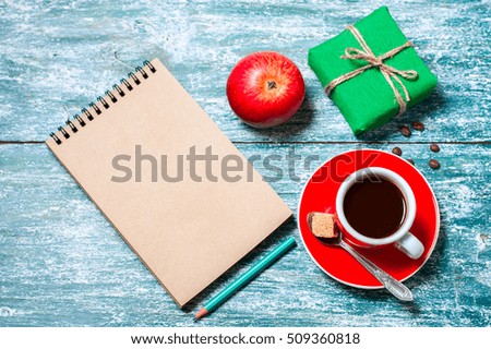 Notepad, cup of coffee, box with gift on a blue wooden table. Space for text, top view