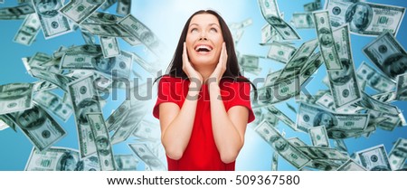 finance, happiness, emotions and people concept - amazed laughing young woman in red dress over money rain and blue background