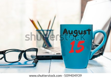 August 15th. Day 15 of month, morning coffee cup with calendar on freelance workplace background. Summer time. Empty space for text