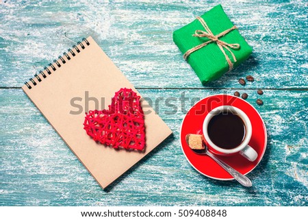 Notepad, cup of coffee, box with gift on a blue wooden table. Space for text, top view