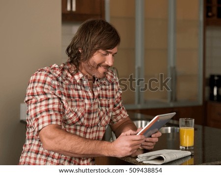 Mid adult man using digital tablet in kitchen