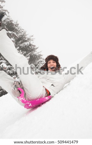cheerful woman sliding with a sled in the snow