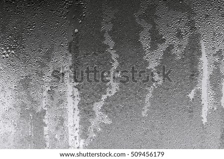abstract background and brilliant texture of black gray color of wet glass with drops of water and with frost or with hoarfrost