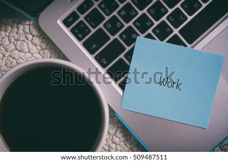 laptop, a cup of black coffee, blue paper sticker with the words work 