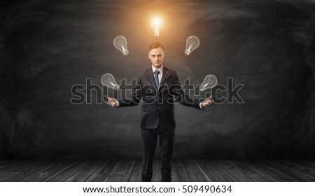 Confident businessman juggles bulbs with one glowing over his head on a black background. Business concept. Good idea is the way to wealth and success. Inspiration and imagination.