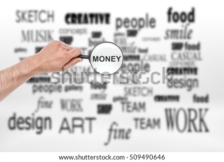 A male hand with a magnifying glass with the word 'money' in it over a collage with a lot of terms on the white background. Business and management. Secrets of success. Earning money. Design and art.