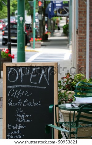 Open sign and menu on sidewalk, outside a cafe.