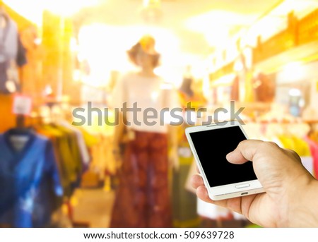 Man using a mobile phone, blur image of  clothes shop as background.
