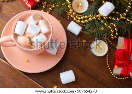 cup of hot cocoa with marshmallows against rustic background with candels of bokeh
