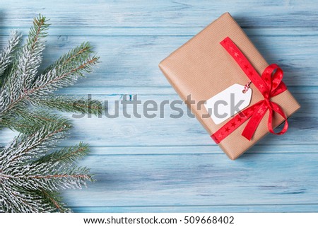 Christmas gift box with tag and fir branch with snow, wooden background, top view
