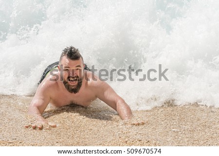 Bearded man at the beach in a wave of the sea