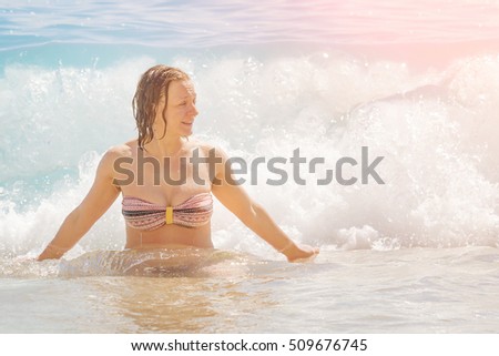Happy woman in the sea waves in the sunlight