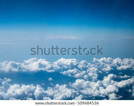 View of the cloudy sky from the airplane's window. Picture of the blue sky with white clouds. The foto that was made above the white cumulus.