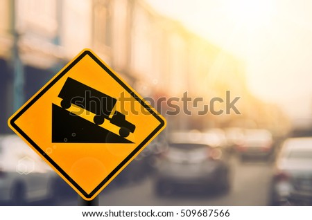 Down hill warning sign on blur traffic road with colorful bokeh light abstract background. Copy space of transportation and travel adventure concept. Retro tone filter color style.