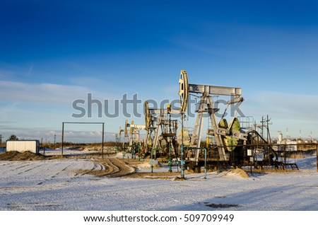 Group of oil pumps and wellheads in the oilfield during winter. Oil and gas concept.