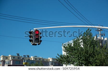 Traffic light showing red signal and time counter. Traffic light hanging over the road with buildings on background.