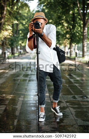 Fashionable black man in park with hat and camera
