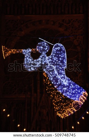 Strasbourg (France) Christmas illumination garlands with trumpeting angel  and cathedral at background. 