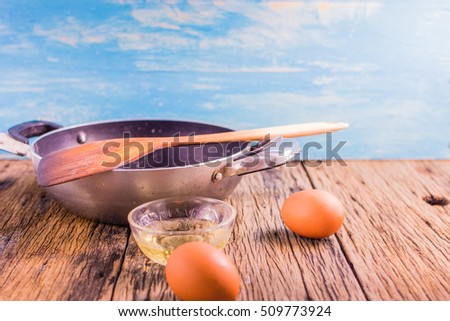 Focus spot on raw material and equipment, making fried eggs on the old wooden table. In the morning, egg fried food is simple and fast.