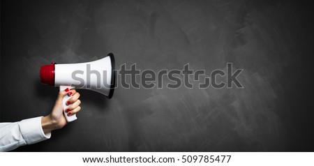 hand with a megaphone in front of an empty blackboard Royalty-Free Stock Photo #509785477