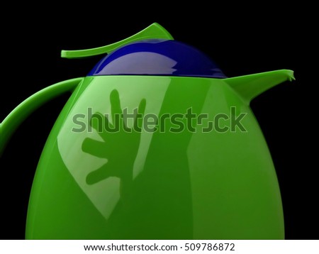 Modern Kettle on a black background with clipping path. Thermos with reflection of stretching hand. Symbols - hot drink, coffee, rest, tea, cooking, comfort, life, morning, ceremony.