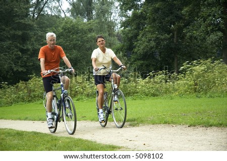 Active senior couple biking in the park.