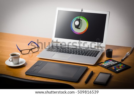 Photographer's workspace with calibrator or profiler attached to laptop's display to get accurate colors