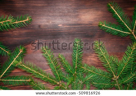 Christmas tree twigs of spruce on a wood background arranged in frame pattern