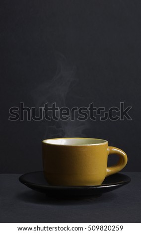 Vintage coffee yellow clay cup about the ferry on a black saucer. Dark background. Retro. Vertical shot