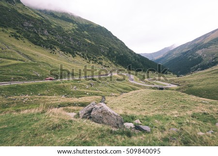 View to the carpathian mountains war road transfagarasan from the top with lonely trees and clouds above - vintage film look