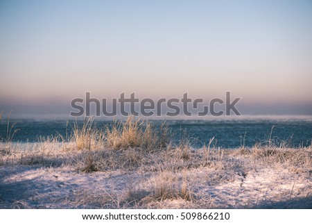 frozen beach view by the baltic sea with sand and ice in water - vintage effect