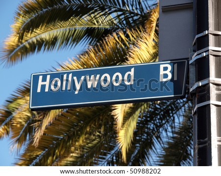 Hollywood Blvd street sign with tall palm trees.