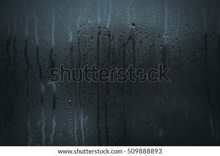 Flowing down water drops on glass