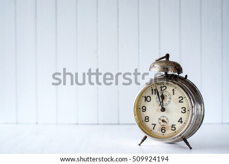 Old alarm clock on a white wooden background - selective focus, copy space