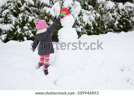 Light hair girl in pink hat play with snow, make snowmen