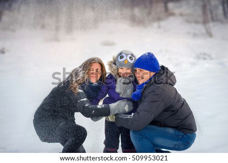 happy family poses on a snow glade, beautiful snow falls, a close-knit cheerful family, parents together with the daughter, on the eve of a holiday of Christmas